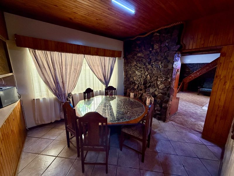 Dining area featuring a rustic stone feature wall, timber ceiling, and tiled flooring, providing a warm and traditional atmosphere.