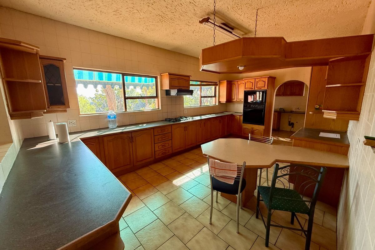 Spacious kitchen featuring extensive wooden cabinetry, built-in oven, gas hob, and a breakfast nook, offering a functional layout with potential for modern updates.