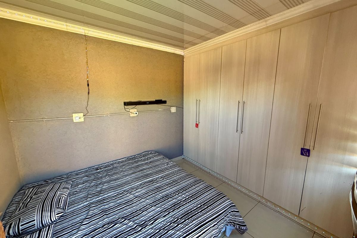 Bedroom featuring extensive built-in cupboards, tiled flooring, and a coved ceiling. The room requires cosmetic updates to address exposed wiring and dated finishes.