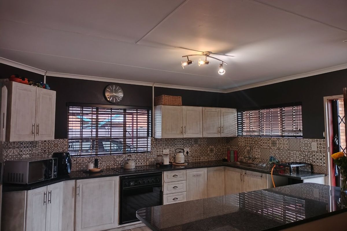 A well-maintained kitchen featuring dark granite countertops, light-toned cabinetry, patterned tile backsplash, and a built-in oven with a functional layout.
