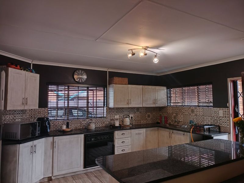 A well-maintained kitchen featuring dark granite countertops, light-toned cabinetry, patterned tile backsplash, and a built-in oven with a functional layout.