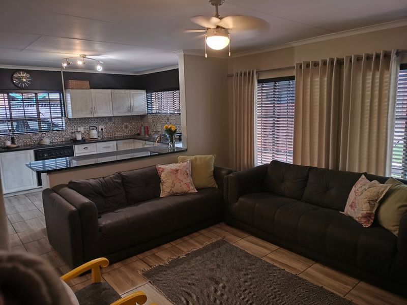 Open-plan living area featuring a functional kitchen with built-in cabinetry, tiled flooring, and a breakfast bar, seamlessly connected to the lounge space.