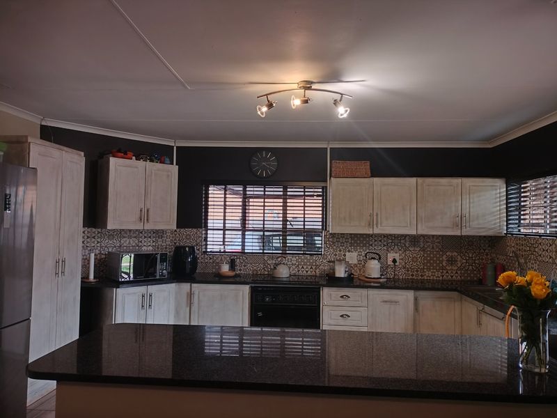 A well-maintained kitchen featuring granite countertops, patterned tile backsplash, and ample built-in cabinetry with a functional layout.