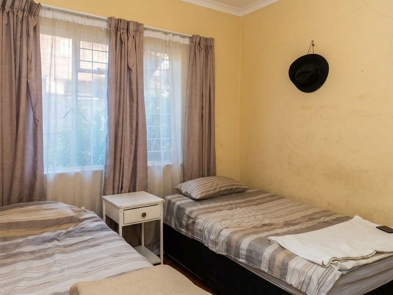 A bedroom featuring a window with curtains and visible wall plaster cracking, requiring cosmetic attention.