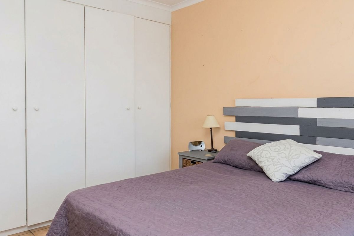 A bedroom featuring a built-in wardrobe with white doors and peach-toned walls, offering a functional space with standard finishes.