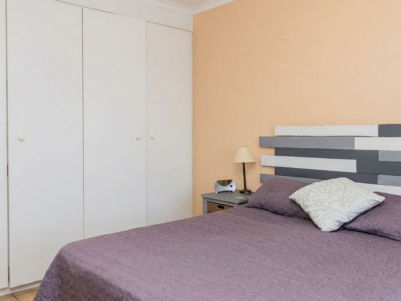 A bedroom featuring a built-in wardrobe with white doors and peach-toned walls, offering a functional space with standard finishes.