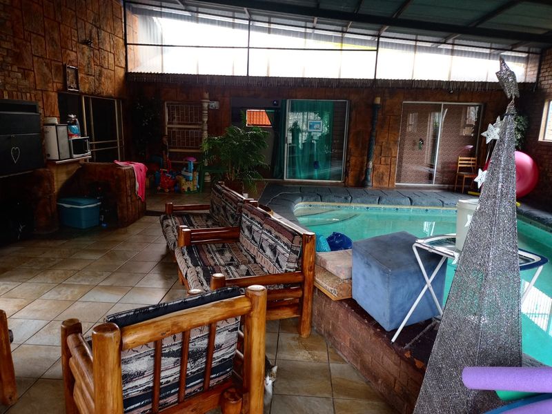 Enclosed indoor pool area featuring stone-clad walls, tiled flooring, and direct access to the home through sliding glass doors.