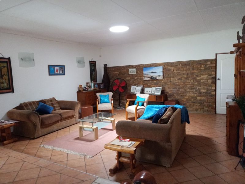 Spacious living room featuring a prominent exposed brick wall and tiled flooring, offering a comfortable and functional layout.