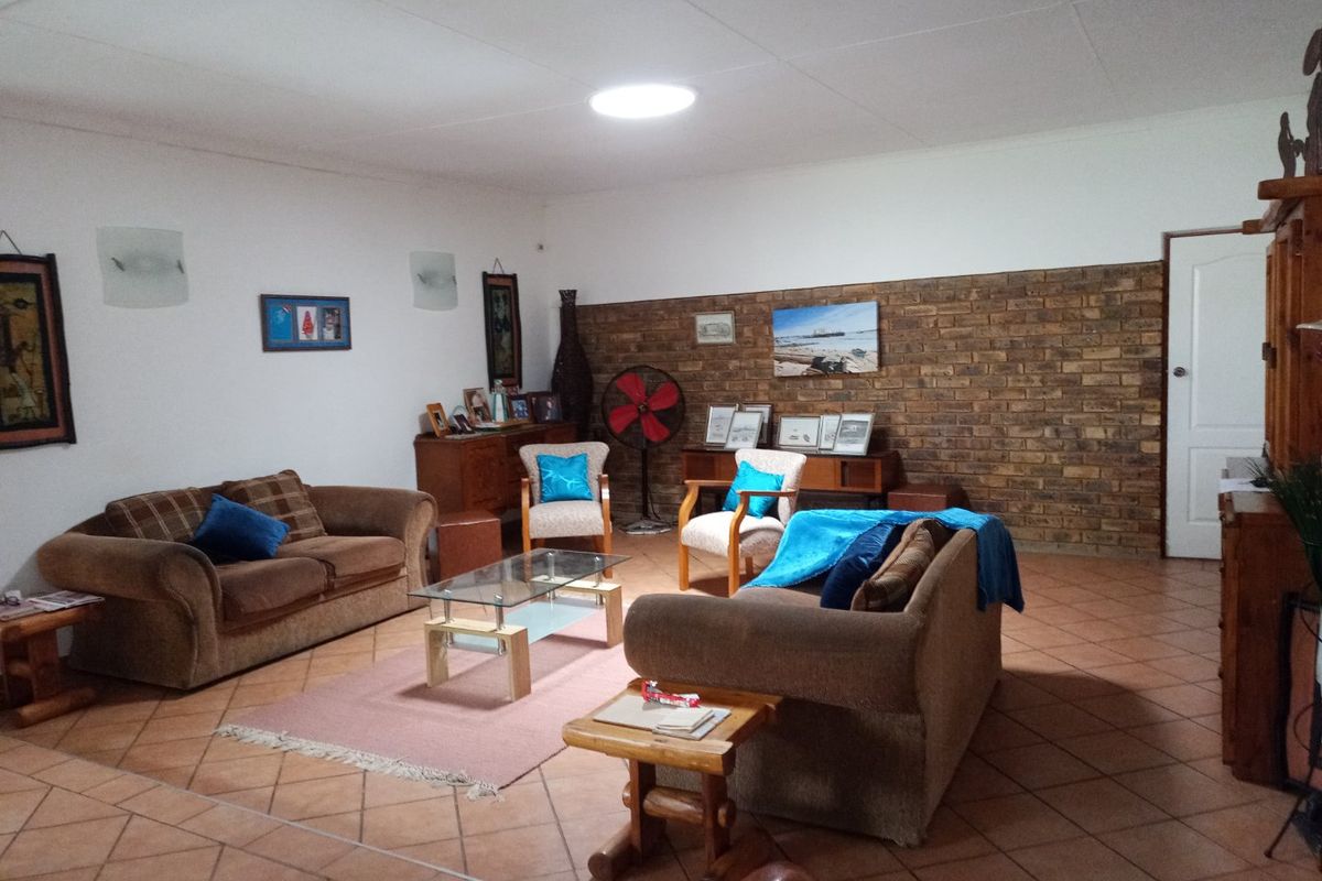 Spacious living room featuring a prominent exposed brick wall and tiled flooring, offering a comfortable and functional layout.