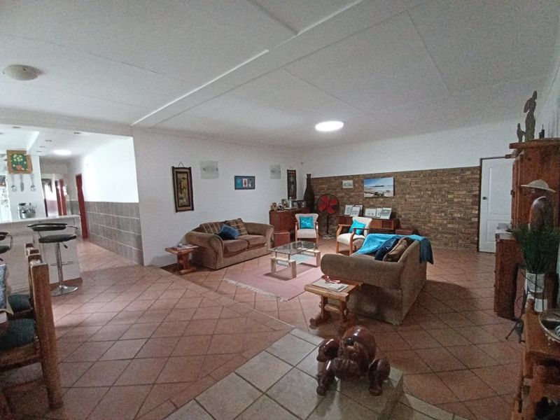 Spacious open-plan living area featuring ceramic floor tiles, an exposed brick feature wall, and a breakfast bar connecting to the kitchen space.