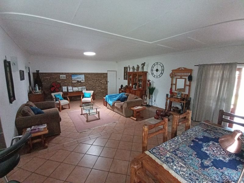Spacious open-plan living and dining area featuring tiled flooring and a decorative brick feature wall.