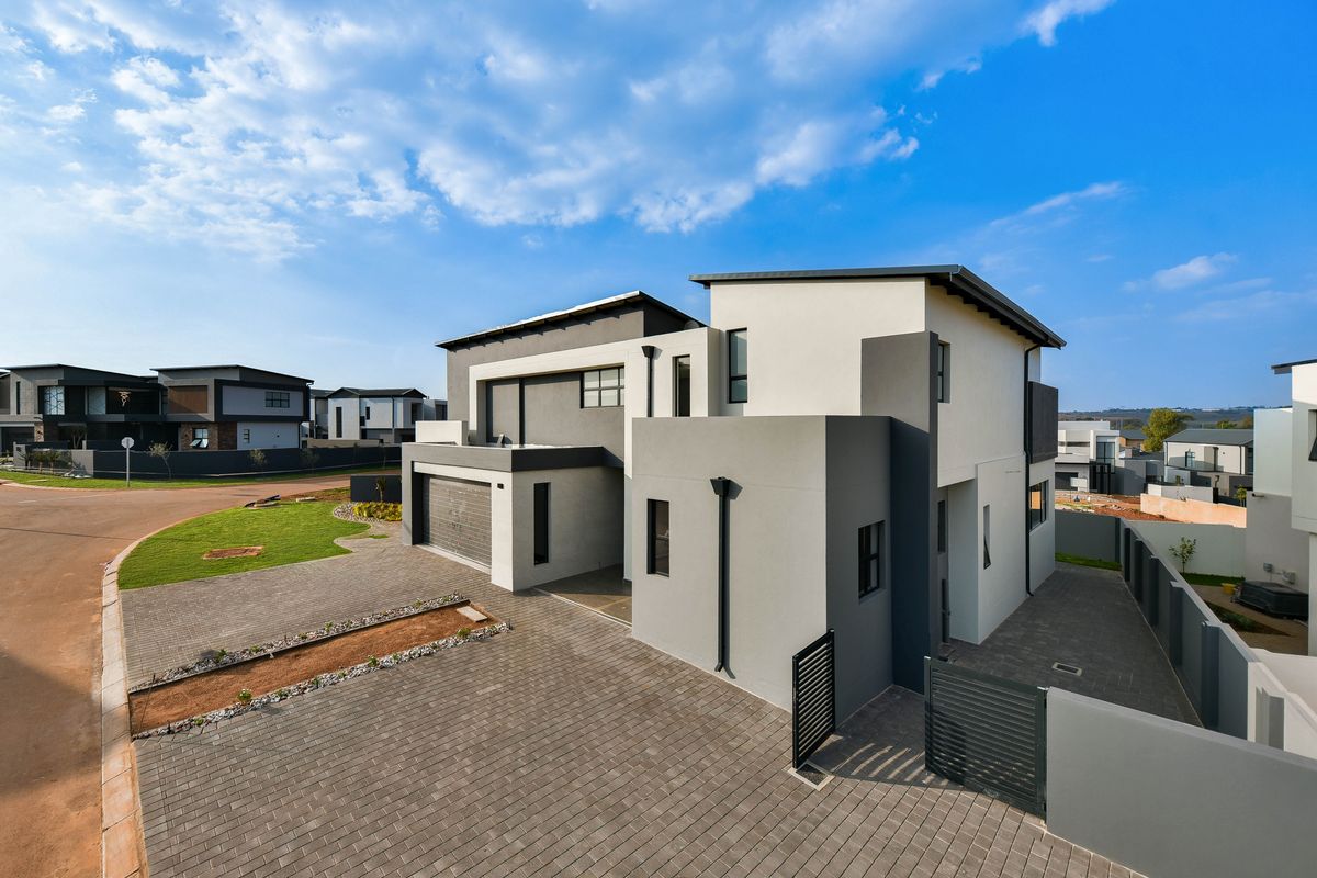 A modern double-story residential property featuring a paved driveway, double garage, and contemporary architectural facade in a secure estate setting.