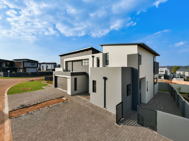 A modern double-story residential property featuring a paved driveway, double garage, and contemporary architectural facade in a secure estate setting.