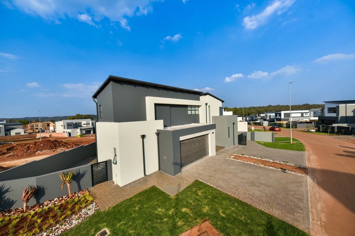 Modern double-story residential property featuring a paved driveway, double garage, and landscaped front garden in a contemporary estate setting.