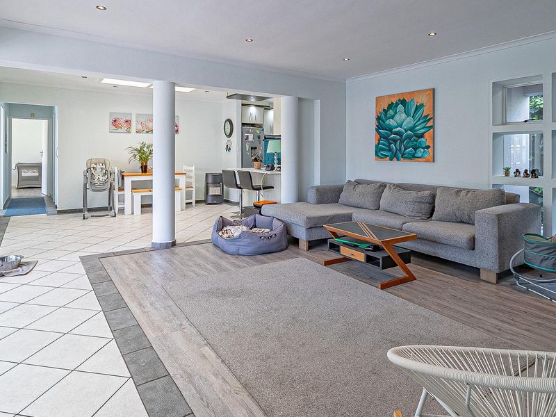 Spacious open-plan living area featuring a blend of tiled and laminate flooring, recessed lighting, and large sliding glass doors leading to the exterior.