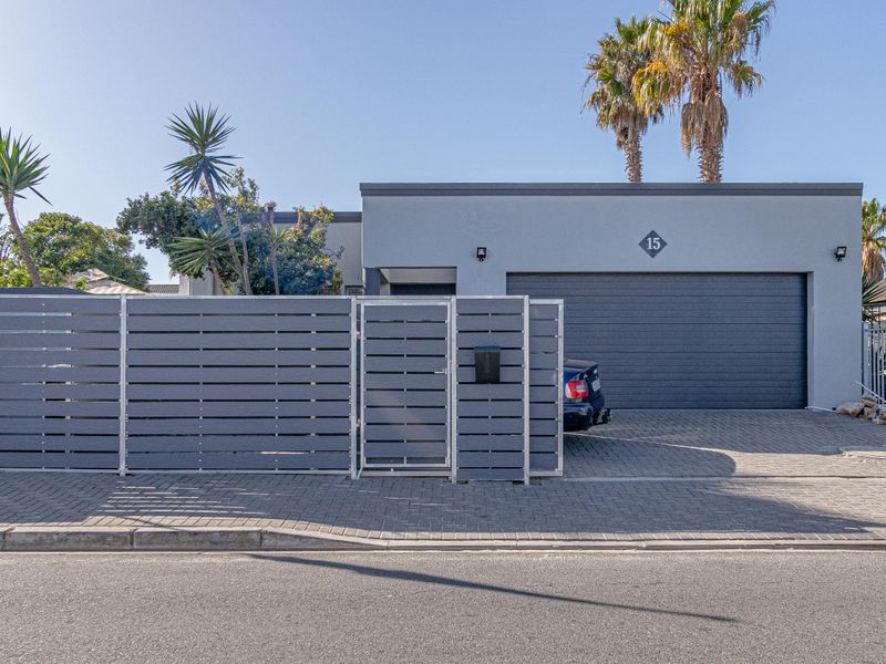 Front elevation of the property featuring a modern slatted privacy fence, paved driveway, and a double garage with a clean, contemporary facade.