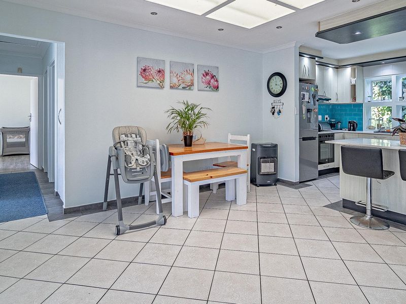 Open-plan kitchen and dining area featuring tiled flooring, modern cabinetry, a central kitchen island, and recessed lighting.