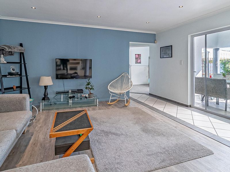 A bright living room featuring laminate flooring, recessed lighting, and large sliding glass doors that provide direct access to the outdoor patio area.