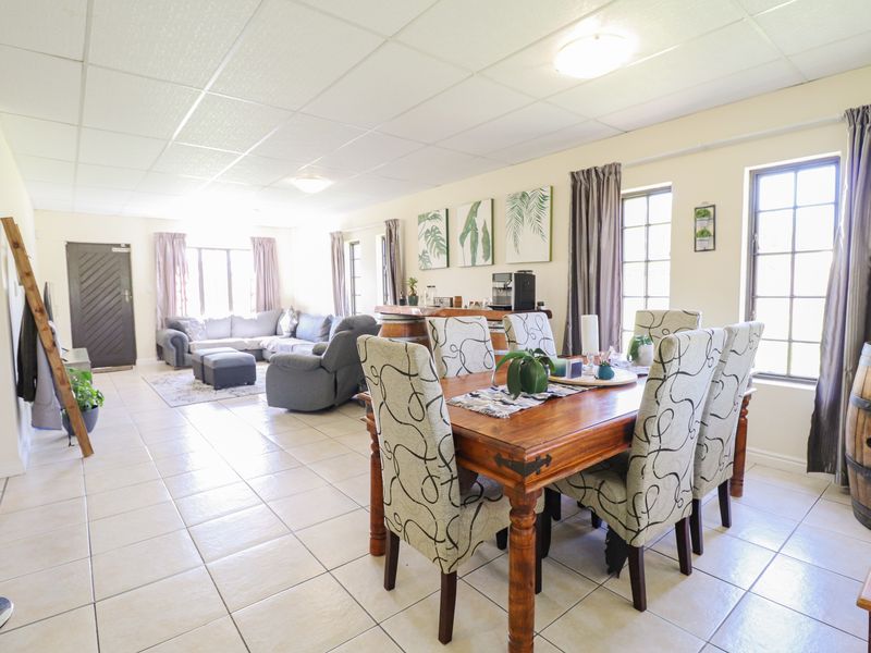 Spacious open-plan living and dining area featuring tiled flooring, a drop ceiling, and a built-in bar counter, offering a versatile layout for entertaining.
