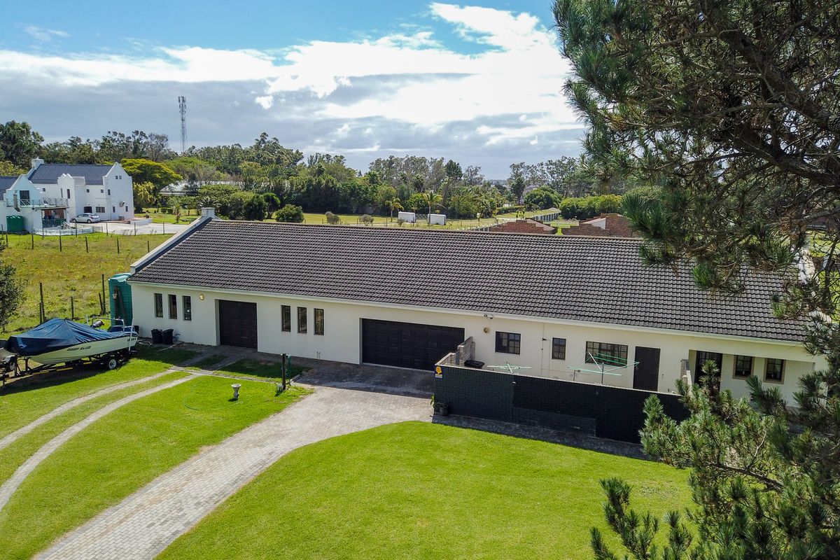 Aerial view of a single-story residential property featuring a tiled roof, paved driveway, and expansive lawn area.