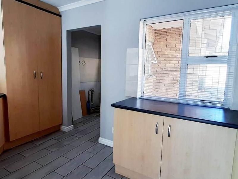 A functional kitchen featuring laminate cabinetry, dark countertops, and tiled flooring, offering a clean canvas for potential cosmetic updates.