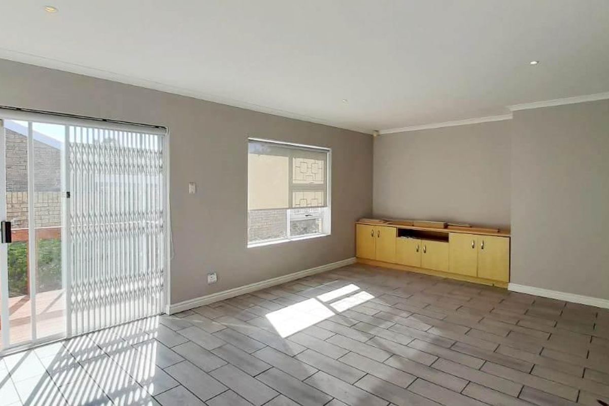 Spacious living room featuring tiled flooring, built-in cabinetry, and a sliding glass door providing access to an outdoor deck area.