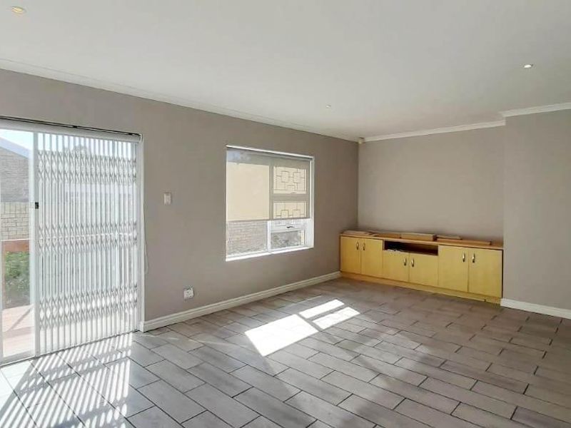 Spacious living room featuring tiled flooring, built-in cabinetry, and a sliding glass door providing access to an outdoor deck area.