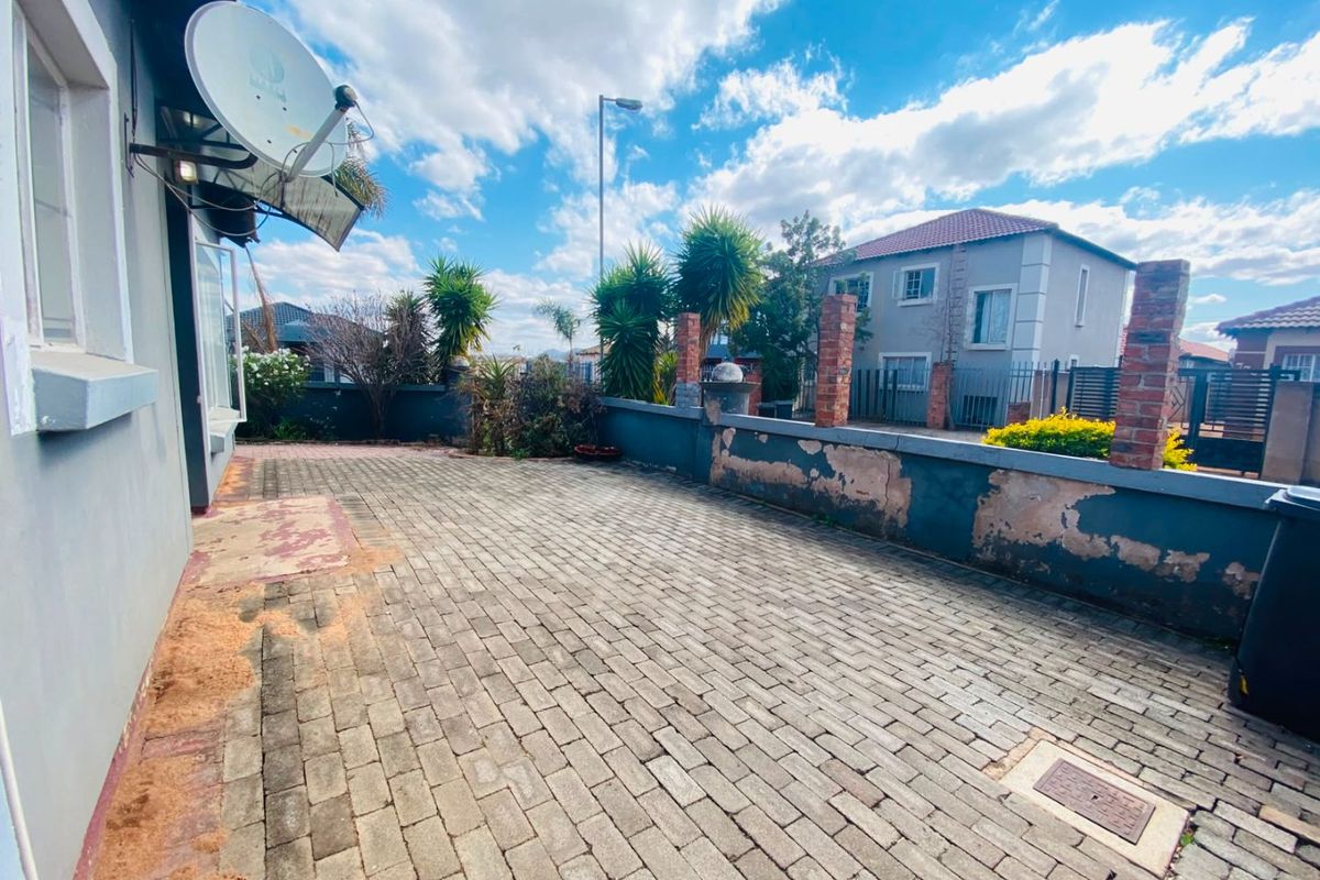 A paved rear courtyard area featuring a boundary wall with brick pillars, requiring maintenance to the wall finish and paving.