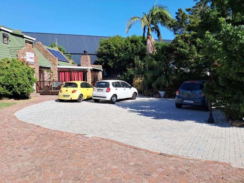 Front exterior view of the property featuring a paved driveway, brick facade, and a timber deck area.