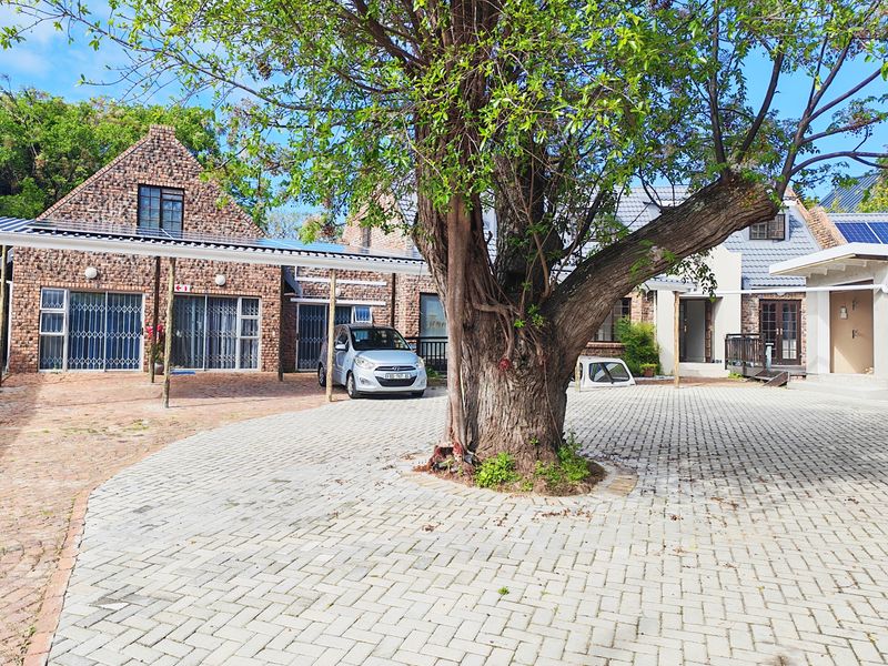 Front exterior view of a brick apartment complex featuring a paved driveway, carport, and solar panel installation.
