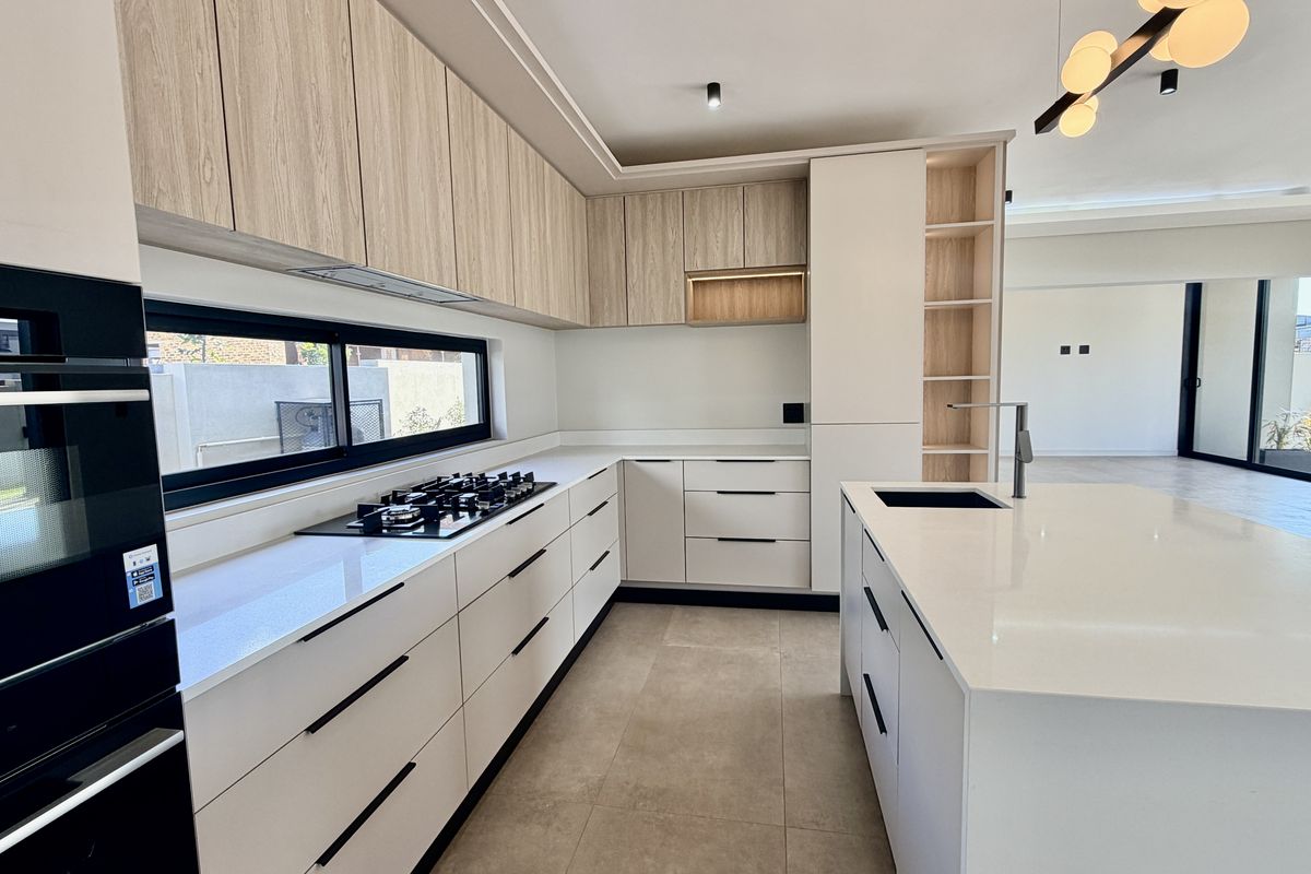 Modern kitchen featuring sleek cabinetry, stone countertops, a central island with a sink, and high-end built-in appliances in an open-plan layout.