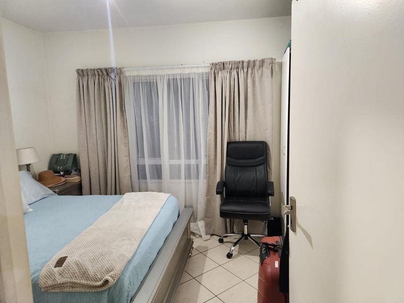 A functional bedroom featuring tiled flooring and a window with curtains, providing a neutral base for personalization.