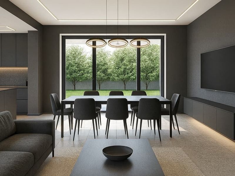 Modern open-plan living and dining area featuring sleek built-in cabinetry, recessed lighting, and large sliding doors opening to a landscaped garden.
