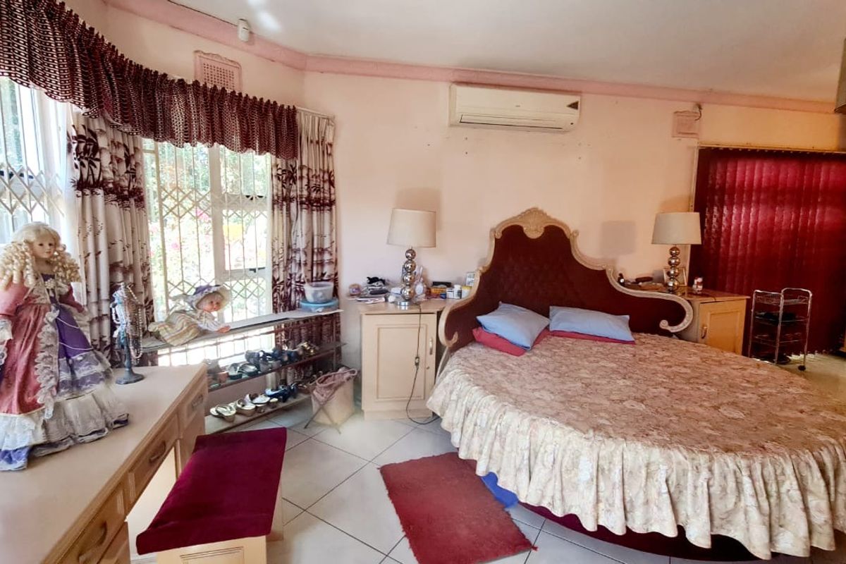 Spacious bedroom featuring tiled flooring, built-in cabinetry, and a wall-mounted air conditioning unit.
