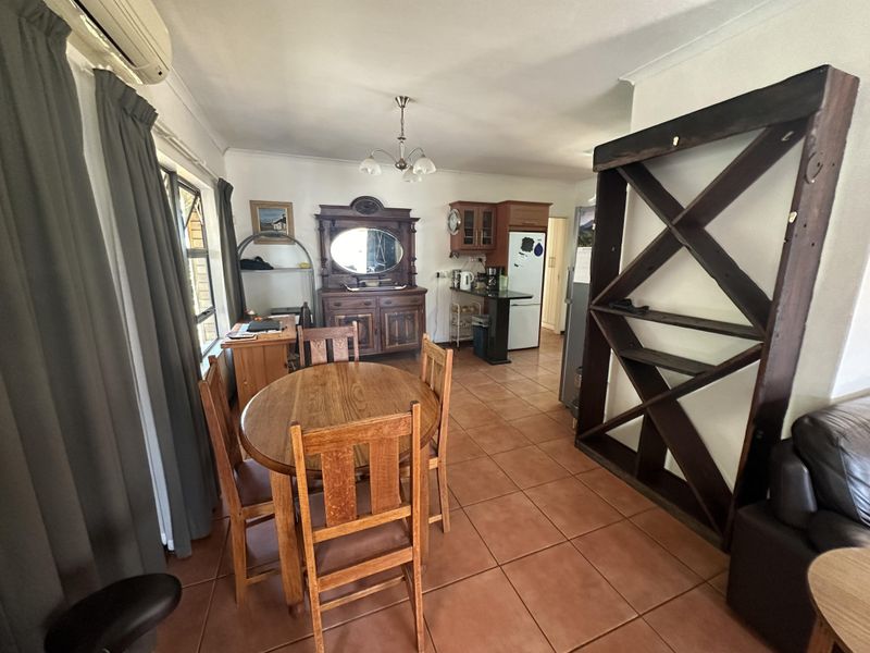 Open-plan living and dining area featuring tiled flooring, a wall-mounted air conditioning unit, and an integrated kitchen space.