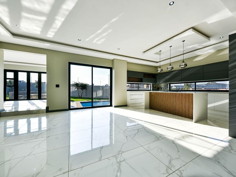Spacious open-plan living and kitchen area featuring high-gloss marble-look floor tiles, modern cabinetry, and large sliding doors opening to the pool area.