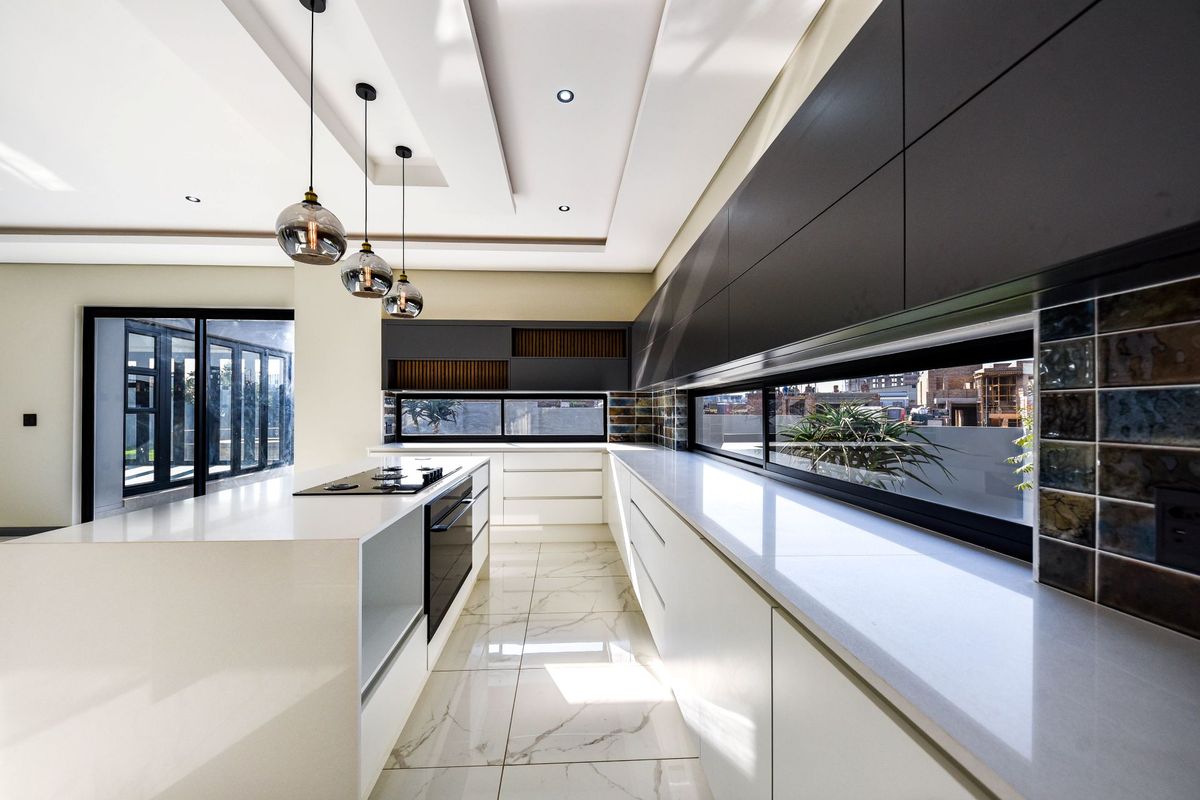 Modern, high-end kitchen featuring sleek cabinetry, quartz countertops, built-in appliances, and large windows that provide ample natural light.