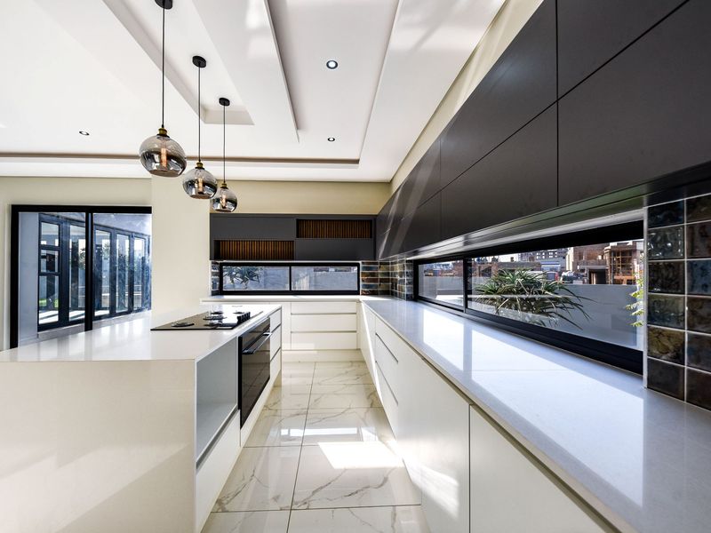 Modern, high-end kitchen featuring sleek cabinetry, quartz countertops, built-in appliances, and large windows that provide ample natural light.