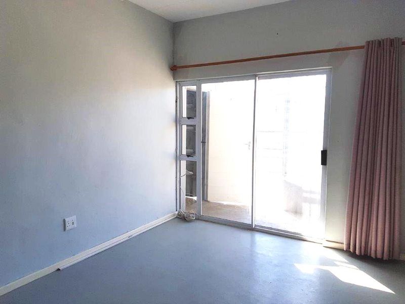 An empty bedroom featuring a sliding glass door that provides access to an outdoor area, finished with neutral walls and flooring.