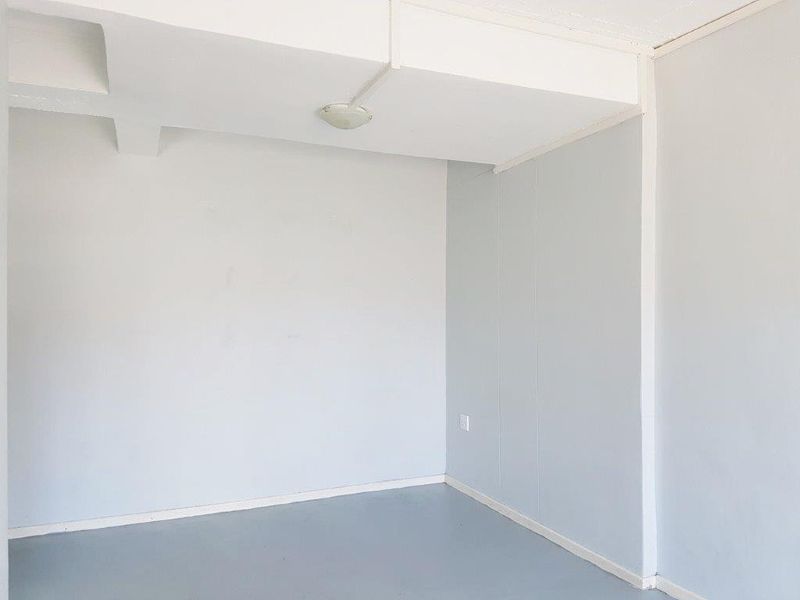 An empty, neutral-toned room featuring basic ceiling lighting and electrical outlets, suitable for use as a bedroom or home office.