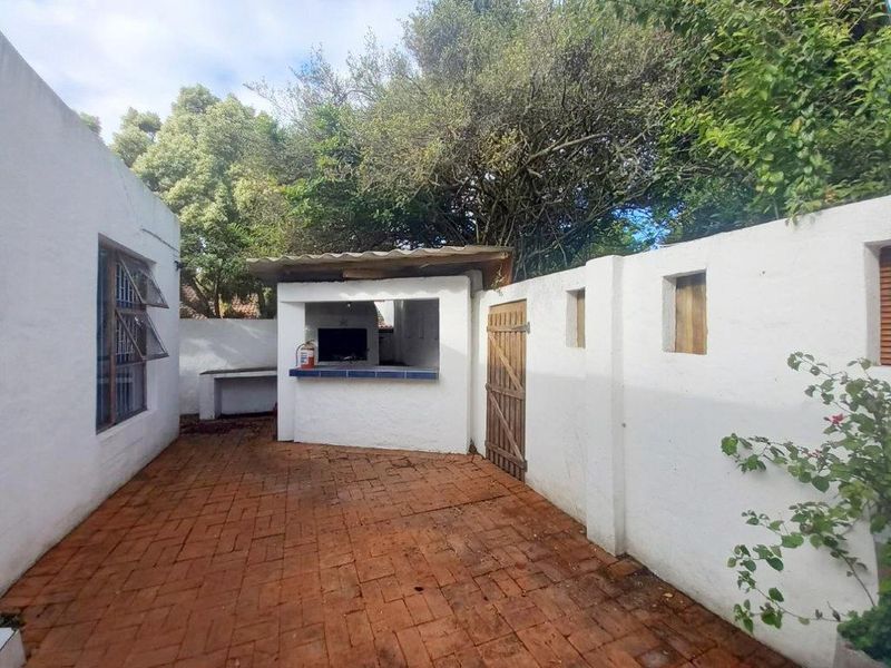 Outdoor patio area featuring a built-in braai, brick paving, and enclosed boundary walls, offering a private space for outdoor entertaining.