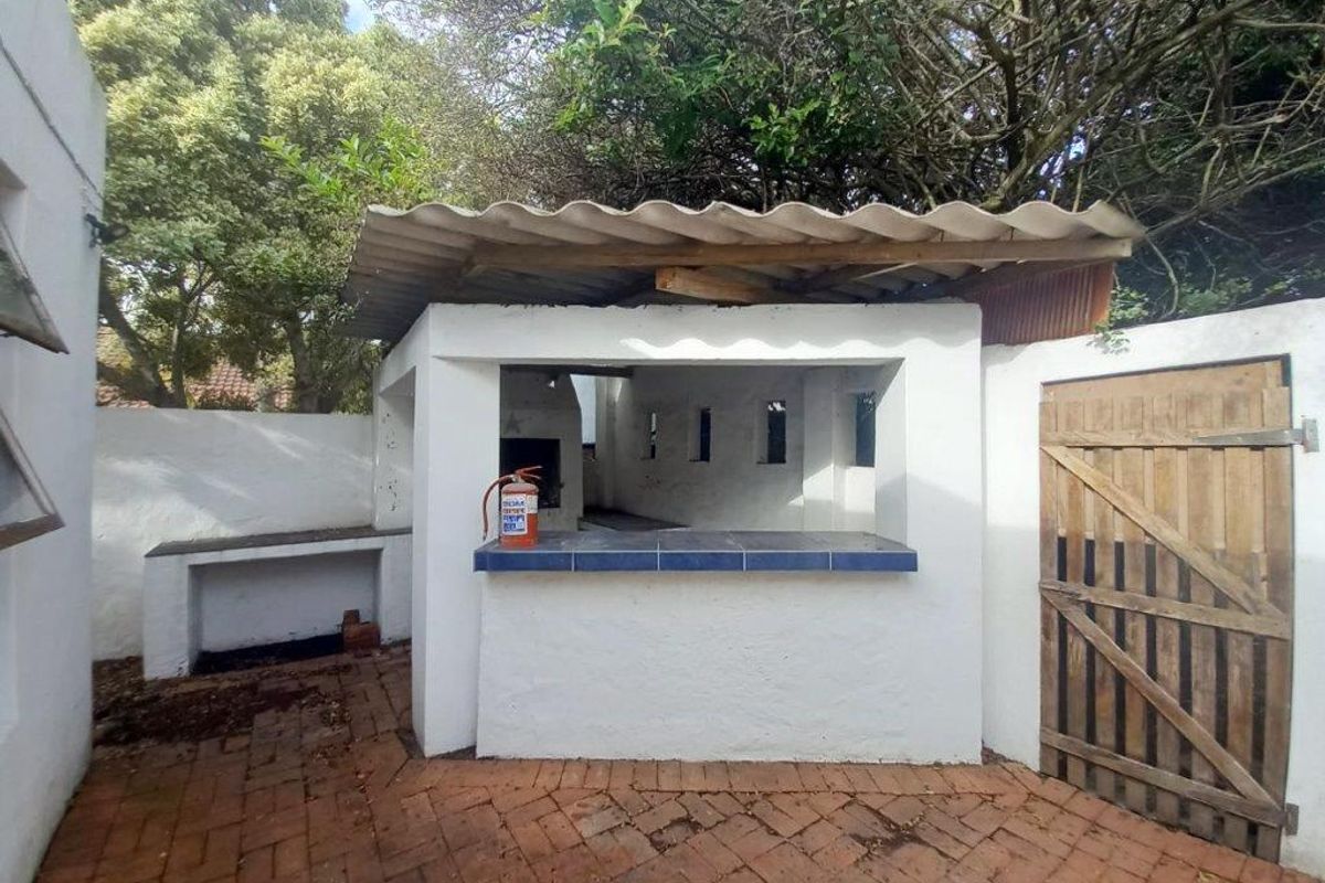 Outdoor entertainment area featuring a built-in braai, tiled counter space, and brick paving, set within a private rear courtyard.