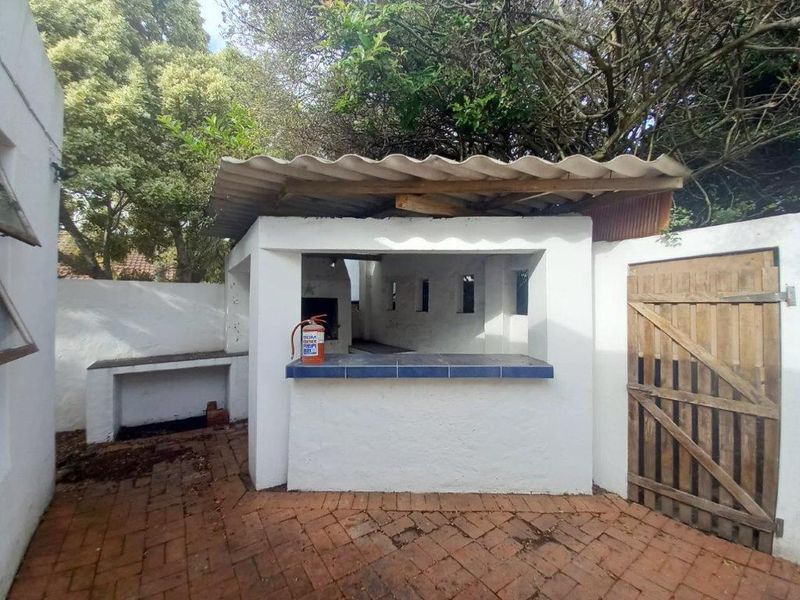 Outdoor entertainment area featuring a built-in braai, tiled counter space, and brick paving, set within a private rear courtyard.