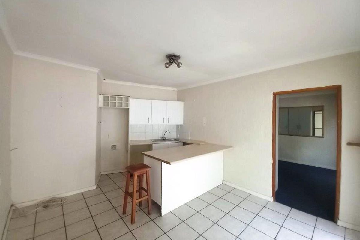 A functional kitchen area featuring tiled flooring, built-in cabinetry, and a breakfast bar, offering a blank canvas for potential renovation and modernization.