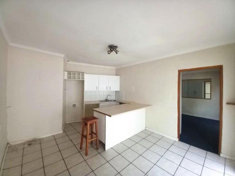 A functional kitchen area featuring tiled flooring, built-in cabinetry, and a breakfast bar, offering a blank canvas for potential renovation and modernization.
