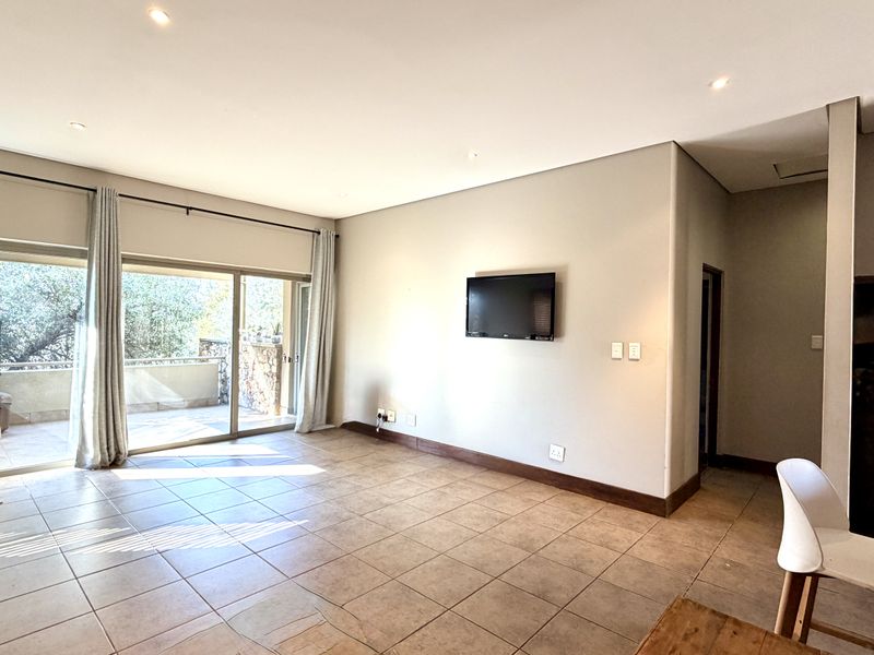 Spacious living area featuring neutral tiled flooring, recessed downlighting, and large sliding glass doors providing access to an outdoor patio.
