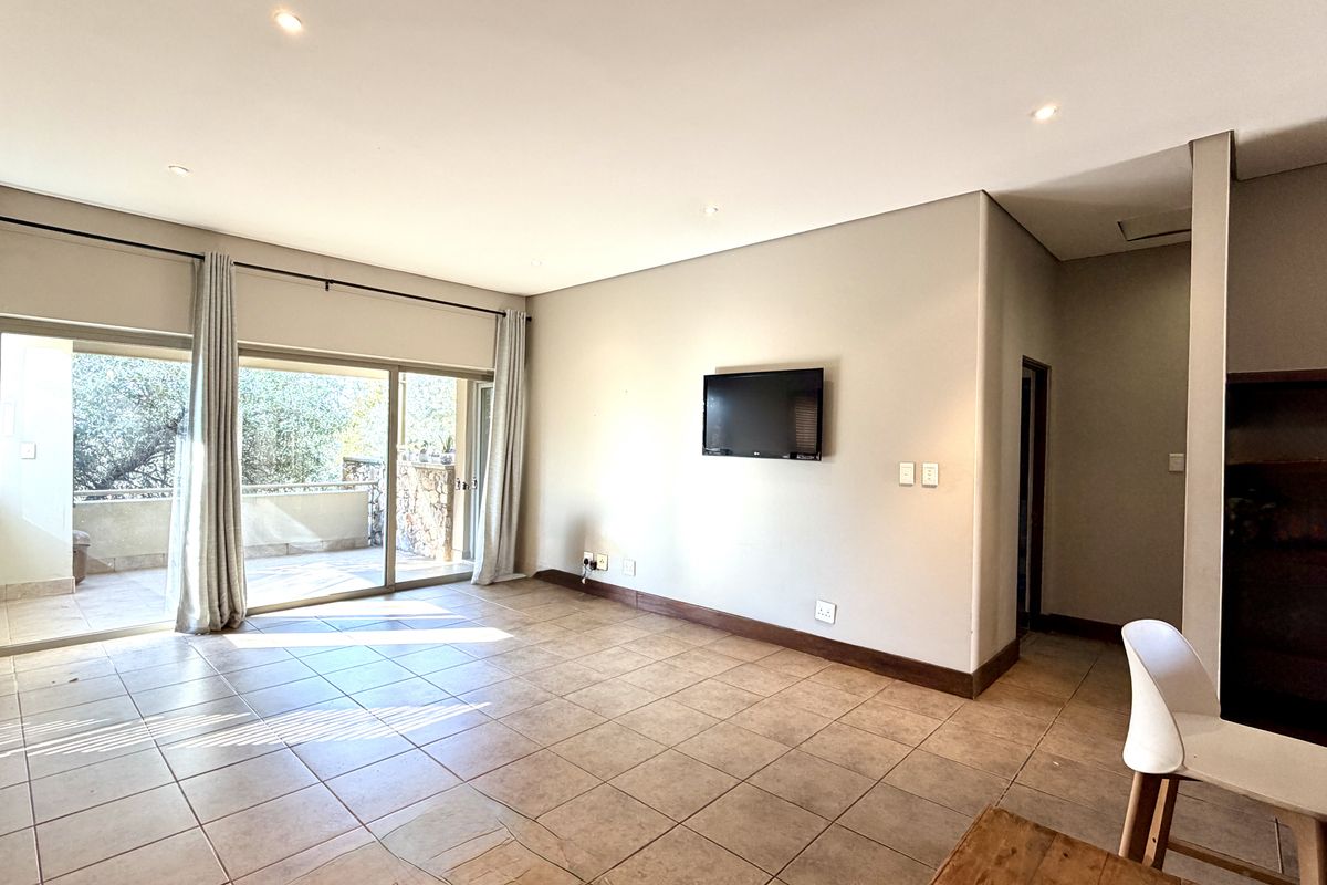 Spacious living area featuring neutral tiled flooring, recessed downlighting, and large sliding glass doors providing access to an outdoor patio.