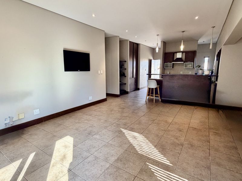 Spacious open-plan living area featuring tiled flooring, recessed lighting, and a functional kitchen with built-in cabinetry and a breakfast island.
