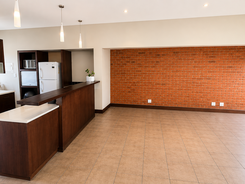Spacious open-plan kitchen and living area featuring a striking exposed brick wall, modern cabinetry, stone countertops, and neutral tiled flooring.