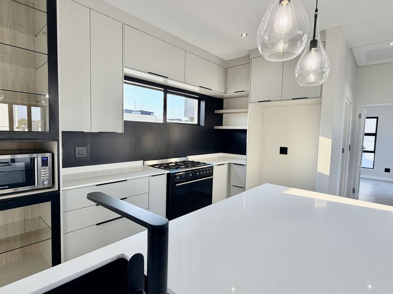 Modern kitchen featuring sleek cabinetry, a central island with quartz countertops, built-in appliances, and high-quality finishes throughout.